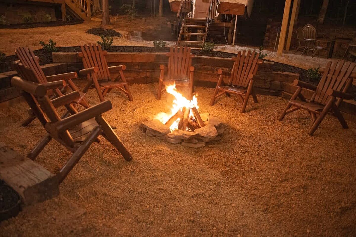 A fire pit surrounded by wooden chairs in an outdoor setting.