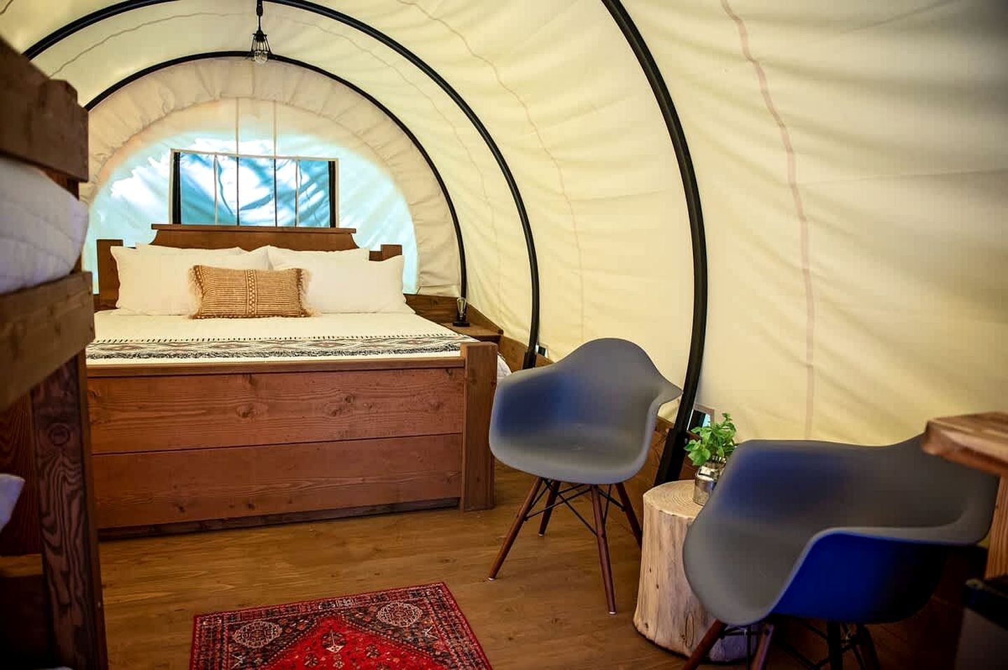 Una carpa con una cama, dos sillas, una mesita y una alfombra.