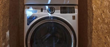Una lavatrice e un'asciugatrice affiancate in una stanza con pareti in legno e pavimento decorato.