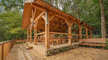 A wooden pavilion with a stone foundation, surrounded by a wooden deck and benches.