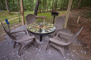 A round glass table with four chairs, surrounded by gravel.