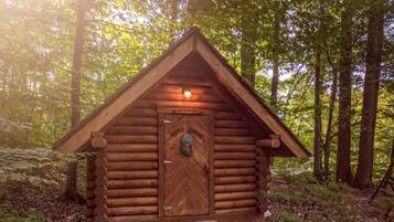 Una cabaña de madera con puerta de parquete, rodeada de un bosque.