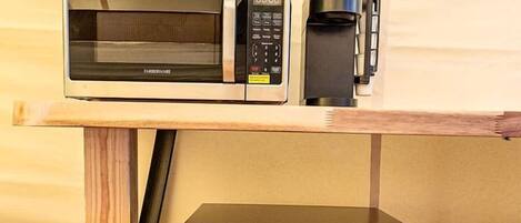 Un refrigerador compacto con el logotipo de Hisense, un microondas y una cafetera Keurig sobre una mesa de madera.