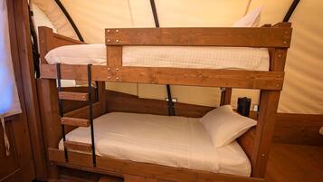 Una cama litera con estructura de madera y ropa de cama blanca dentro de una estructura tipo tienda de campaña.