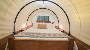 Ein Zelten-ähnliches Zimmer mit einem Bett, einem Fenster und einer Hängelampe.