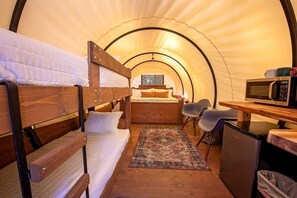 A cozy interior with bunk beds, a desk, a microwave, and a small refrigerator.