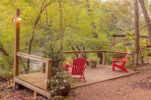 A wooden deck with a railing, two red chairs, and a potted plant.