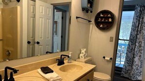 A bathroom with two sinks, a toilet, a mirror, a towel rack, and a window with a view.