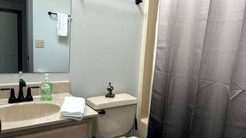 A bathroom with a sink, toilet, and shower curtain.