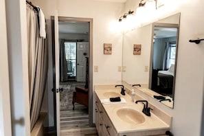 A bathroom with two sinks, a large mirror, and a door leading to a hallway.