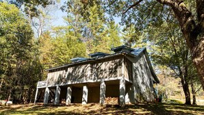A rustic cabin with a porch, surrounded by trees.