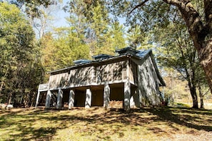 A rustic cabin with a porch, surrounded by trees.