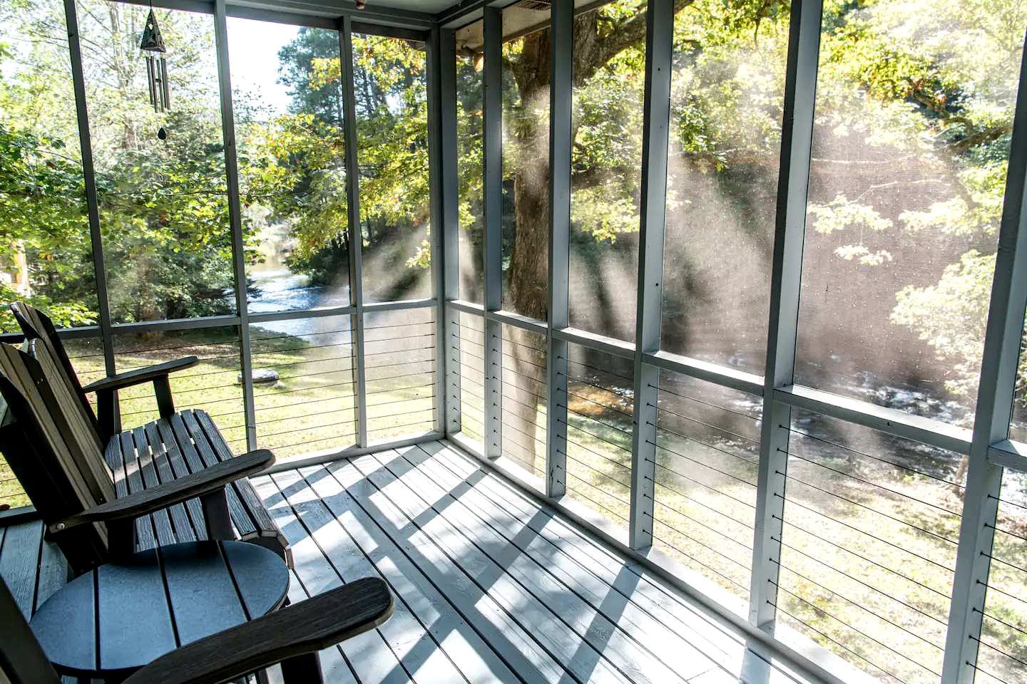A covered outdoor area with a wooden deck, a bench, and a view of a natural landscape.