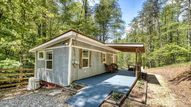 A cabin with a covered porch, a gravel driveway, and a forested backdrop. - Cozy Cabin with Direct Access to the Toccoa River, a Perfect Escape for Fishing Lovers in Suches, Georgia (Suches)