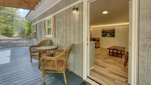 A wooden deck with wicker furniture, a door leading to an interior with a painting and a table. - Cozy Cabin with Direct Access to the Toccoa River, a Perfect Escape for Fishing Lovers in Suches, Georgia (Suches)