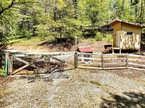 Una struttura in legno con tetto rosso, un piccolo deposito e un ingresso con cancello.