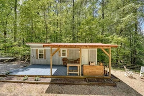 A cabin with a wooden deck, a covered porch, and a small seating area. - Cozy Cabin with Direct Access to the Toccoa River, a Perfect Escape for Fishing Lovers in Suches, Georgia (Suches)