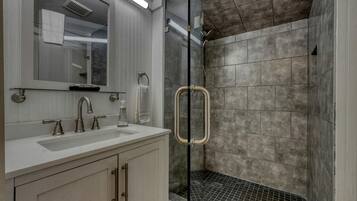 A modern bathroom with a glass shower enclosure, a sink with a mirror, and a towel rack.