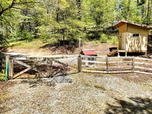 Une structure en bois avec un toit rouge, un petit abri et une entrée fermée par un portail.