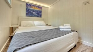 A hotel room with a bed, a painting, a nightstand, and a wall-mounted light. - Cozy Cabin with Direct Access to the Toccoa River, a Perfect Escape for Fishing Lovers in Suches, Georgia (Suches)