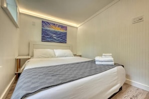 A hotel room with a bed, a painting, a nightstand, and a wall-mounted light. - Cozy Cabin with Direct Access to the Toccoa River, a Perfect Escape for Fishing Lovers in Suches, Georgia (Suches)
