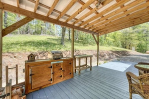 A wooden deck with a grill, a table, and wicker chairs. - Cozy Cabin with Direct Access to the Toccoa River, a Perfect Escape for Fishing Lovers in Suches, Georgia (Suches)