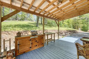 Une terrasse en bois avec un barbecue, une table et des chaises en osier.