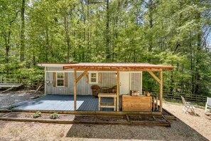 Une cabane dotée d’une terrasse en bois, d’un porche abrité et d’un petit coin salon.