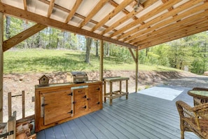 A wooden deck with a grill, a table, and wicker chairs.