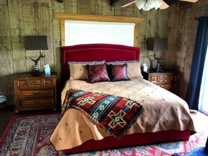 Ein Bett mit rotem Kopfteil, einer gemusterten Decke und einem Holzboden.
