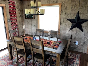 Una mesa de madera rústica con sillas, una decoración de estrella y una ventana con luz natural.