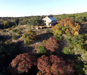 A house with a balcony, surrounded by trees with autumn foliage.