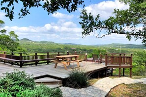 Eine Holzterrasse mit Picknicktischen und Bänken mit Blick auf eine üppige grüne Landschaft.