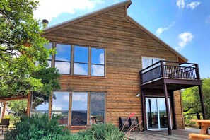 Ein zweistöckiges Holzhaus mit großen Fenstern, einem Balkon und einer Terrasse.
