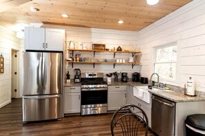 Una cocina moderna con electrodomésticos de acero inoxidable, estantes de madera y un ventanal.