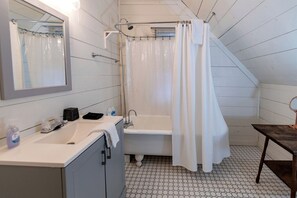 Ein Badezimmer mit Badewanne, Waschbecken, Spiegel und Duschvorhang.