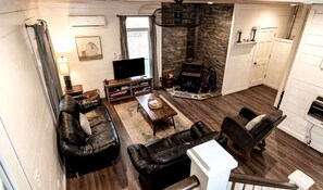 Una sala de estar con chimenea, sofás de cuero, televisor y una pared de acento de piedra.