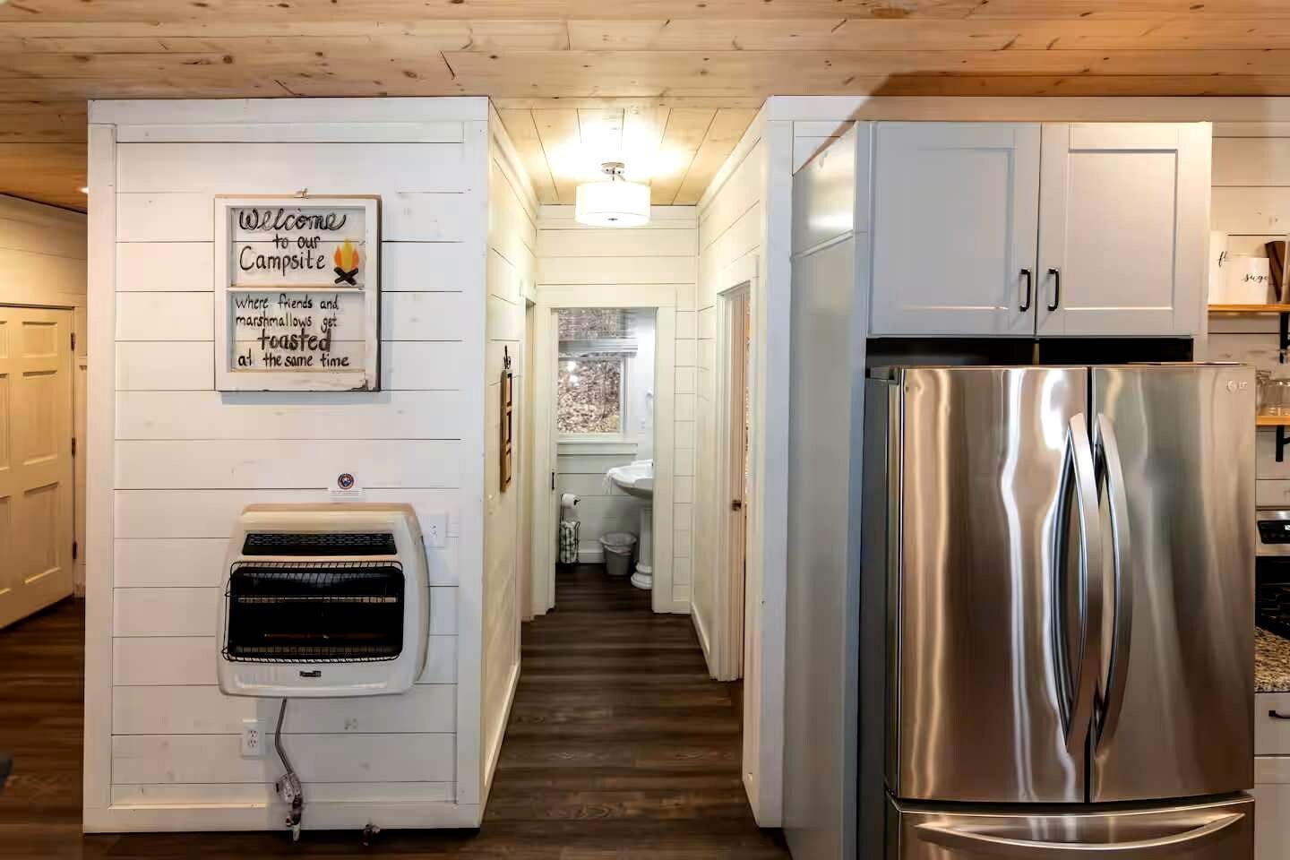 A kitchen with white cabinets, a stainless steel refrigerator, and a wall-mounted air heater.