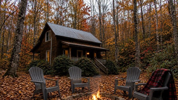 A cabin with a fire pit and three Adirondack chairs in a forest. - Secluded Cabin on Suches Creek and in the National Forest for a Relaxing Georgia Getaway (Suches)