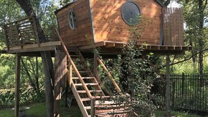 Une nichoir en bois avec une échelle, installé sur une plateforme dans un arbre.