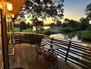 A wooden deck with a table and chairs overlooking a body of water.