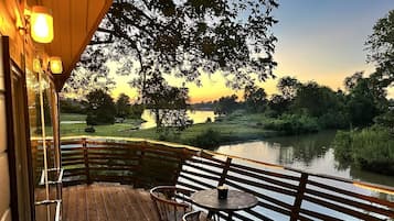 A wooden deck with a table and chairs overlooking a body of water.