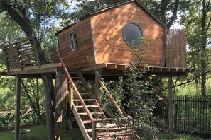 A wooden birdhouse with a ladder on a tree platform. - Gorgeous Tree House Rental with Lake Views for Glamping in Texas (Willis)