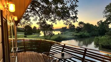 A wooden deck with a table and chairs overlooking a body of water.