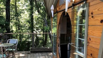 A wooden cabin with a deck, a glass door, and a potted plant.
