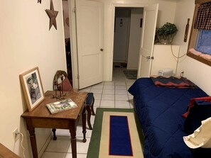 Una habitación pequeña con una cama, una mesa con una silla, un cuadro enmarcado y una decoración con forma de estrella en la pared.