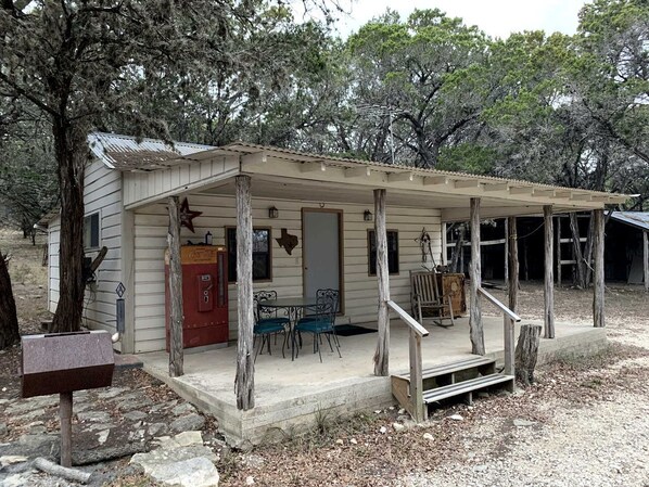 A rustic cabin with a porch, a table with chairs, and a mailbox.