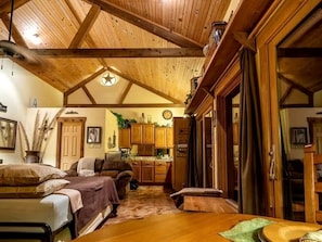 A cozy cabin interior with a wooden ceiling, a dining area, and a kitchen. - Pet-Friendly Cabin Rental with Creekside Views near Bandera, Texas (Pipe Creek)