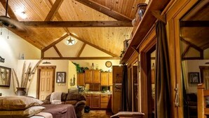 A cozy cabin interior with a wooden ceiling, a dining area, and a kitchen.