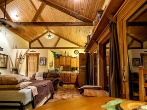 A cozy cabin interior with a wooden ceiling, a dining area, and a kitchen.